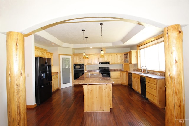19801 Pinehaven Ln, Lenore, ID 83541 - kitchen featuring black appliances, a tray ceiling, light brown cabinetry, a kitchen island with sink, and arched walkways