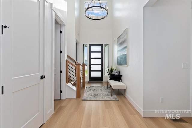 entrance foyer featuring a towering ceiling, an inviting chandelier, and light hardwood / wood-style floors