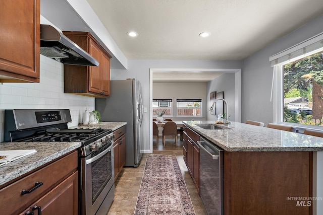 3209 W Plant Dr, Boise, ID 83703 - kitchen featuring appliances with stainless steel finishes, a sink, wall chimney range hood, a kitchen island with sink, and healthy amount of natural light