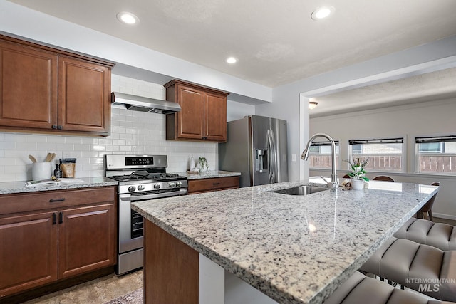 3209 W Plant Dr, Boise, ID 83703 - kitchen with appliances with stainless steel finishes, a sink, wall chimney range hood, a breakfast bar area, and light stone countertops