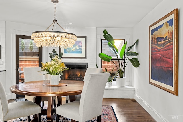 dining space with wood finished floors, baseboards, and a warm lit fireplace