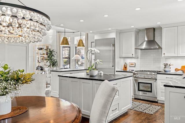 kitchen with tasteful backsplash, a kitchen island, wall chimney range hood, dark wood finished floors, and high quality appliances