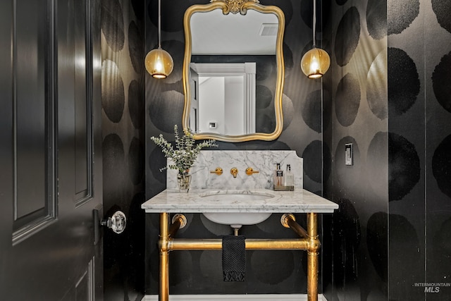 bathroom with a sink, visible vents, and backsplash