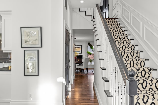 stairs with a high ceiling, wood finished floors, visible vents, and baseboards