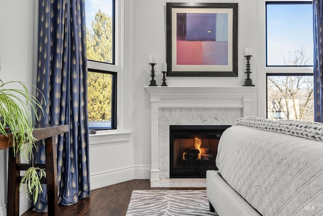 bedroom featuring wood finished floors, baseboards, and a premium fireplace