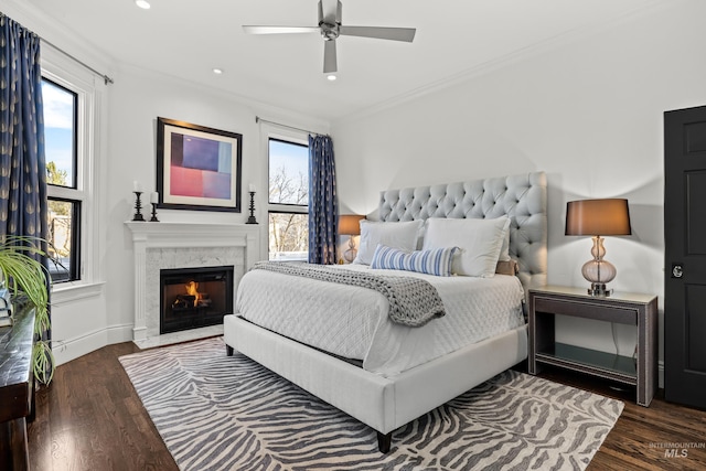 bedroom featuring crown molding, baseboards, a premium fireplace, recessed lighting, and wood finished floors