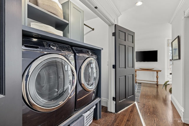 clothes washing area featuring dark wood finished floors, laundry area, crown molding, and washing machine and dryer