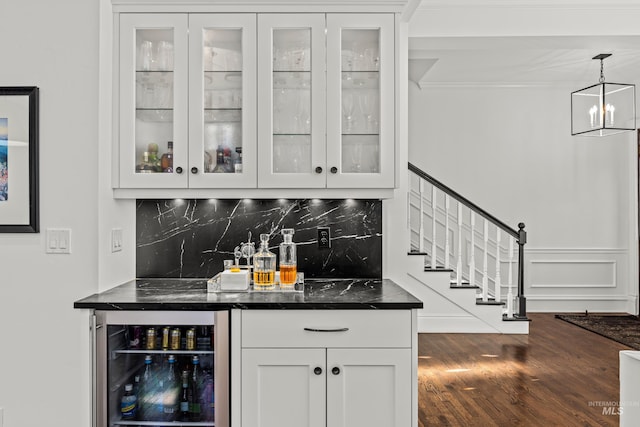 bar featuring backsplash, beverage cooler, stairway, a bar, and dark wood-style flooring