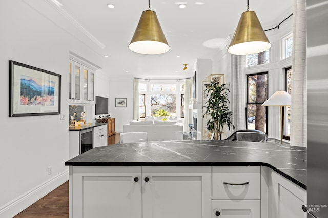 kitchen with beverage cooler, dark countertops, white cabinets, and crown molding