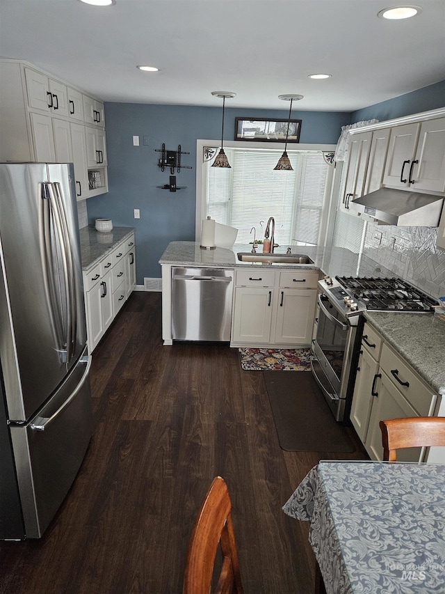 kitchen with appliances with stainless steel finishes, dark hardwood / wood-style floors, white cabinetry, sink, and hanging light fixtures