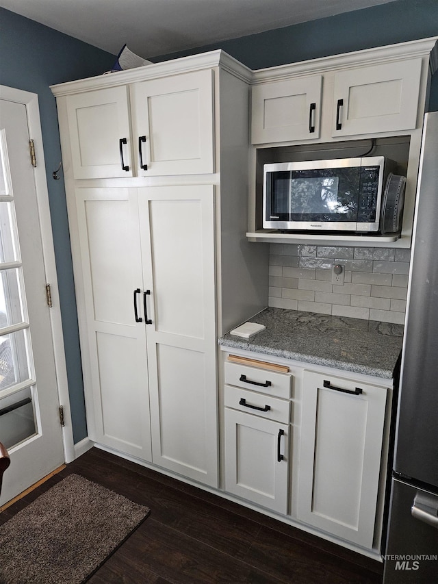 kitchen featuring dark hardwood / wood-style floors, tasteful backsplash, white cabinets, stainless steel appliances, and light stone countertops