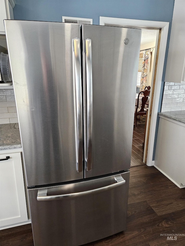 interior details with stainless steel refrigerator, white cabinetry, dark hardwood / wood-style floors, and backsplash