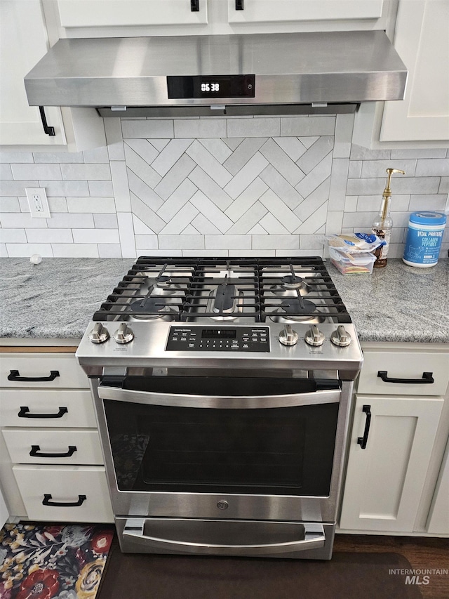 kitchen featuring light stone countertops, stainless steel gas range, decorative backsplash, and white cabinets