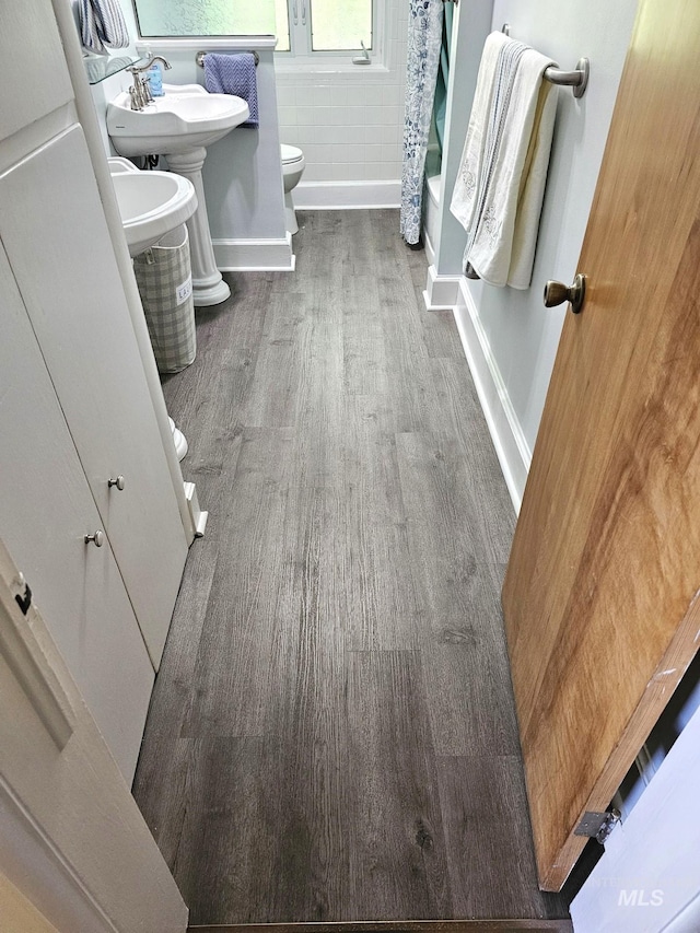 full bathroom featuring hardwood / wood-style flooring, sink, toilet, and shower / bath combination with curtain