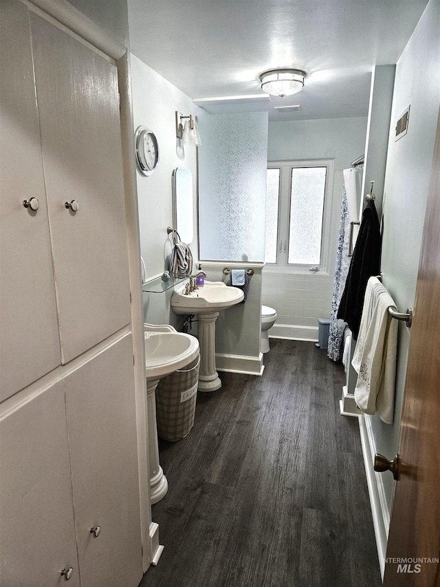 bathroom featuring hardwood / wood-style flooring, curtained shower, and toilet