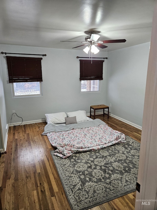 unfurnished bedroom with multiple windows, dark hardwood / wood-style flooring, and ceiling fan