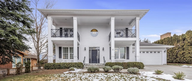 greek revival house featuring a garage, driveway, and a balcony