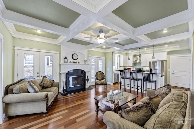 living room with french doors, dark wood-style flooring, a glass covered fireplace, and beam ceiling