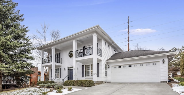 greek revival inspired property featuring a balcony, a garage, and concrete driveway