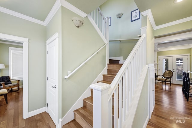 staircase with ornamental molding, french doors, baseboards, and wood finished floors