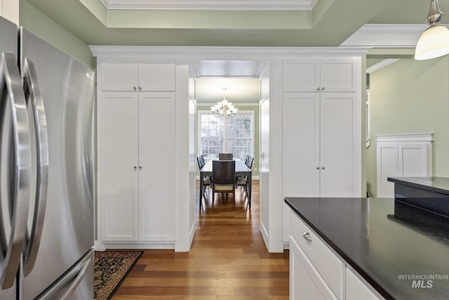 kitchen with dark countertops, ornamental molding, wood finished floors, and freestanding refrigerator