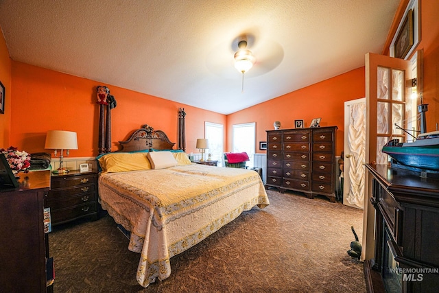 carpeted bedroom featuring a ceiling fan, vaulted ceiling, and a textured ceiling