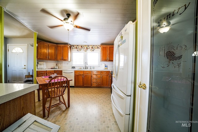 kitchen featuring brown cabinets, light countertops, a sink, ceiling fan, and white appliances