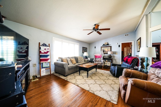 living room with lofted ceiling, visible vents, a textured ceiling, and wood finished floors