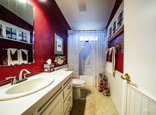 bathroom featuring a textured ceiling, toilet, visible vents, vanity, and shower / bath combo with shower curtain