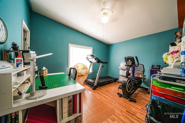 workout area with lofted ceiling, a textured ceiling, a ceiling fan, and wood finished floors