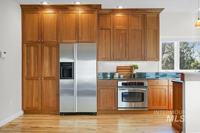 kitchen with dark countertops, light wood finished floors, stainless steel appliances, and brown cabinets