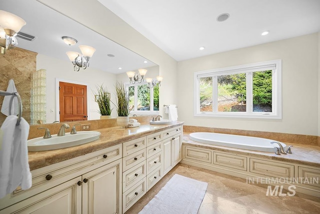 bathroom featuring an inviting chandelier, a sink, a garden tub, and double vanity