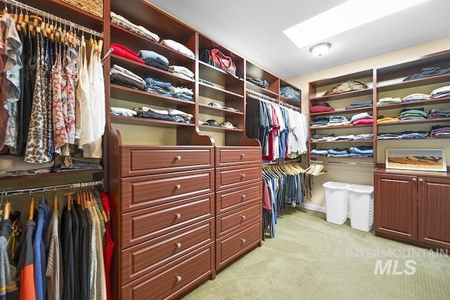 walk in closet with light colored carpet and a skylight