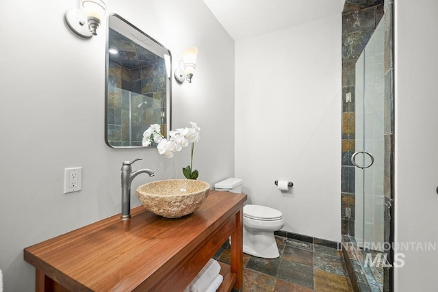 bathroom with vanity, stone finish floor, a stall shower, and toilet