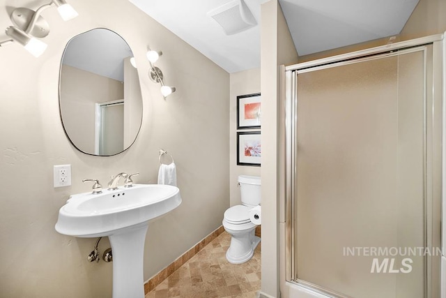 bathroom with stone finish flooring, visible vents, a shower stall, baseboards, and toilet