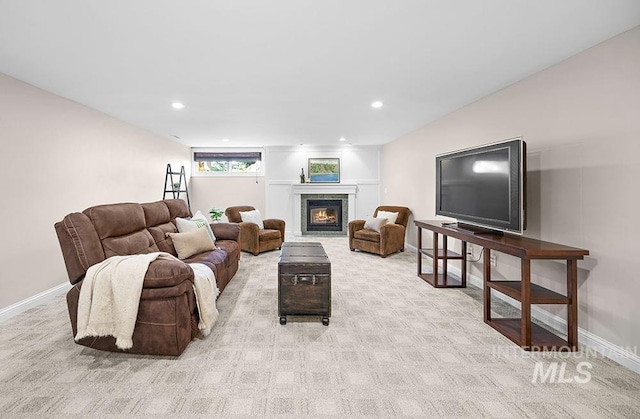 living area with a glass covered fireplace, recessed lighting, and light colored carpet