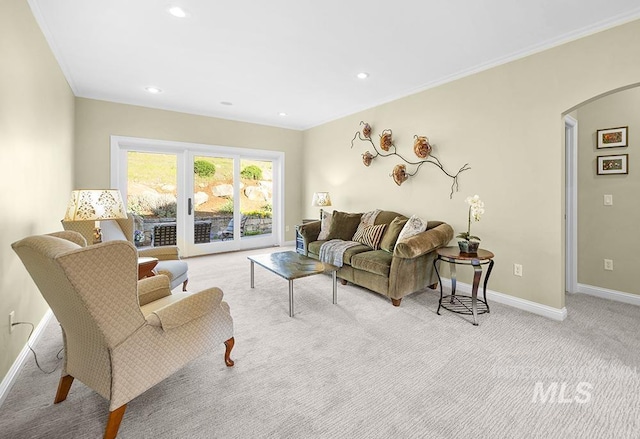 living area featuring arched walkways, baseboards, ornamental molding, light carpet, and recessed lighting