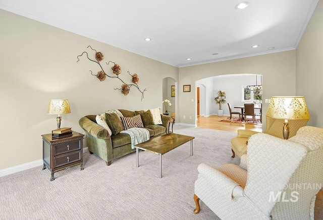 living area featuring arched walkways, baseboards, ornamental molding, and light colored carpet