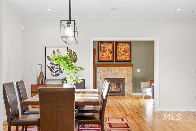 dining space with baseboards, wood finished floors, and a fireplace