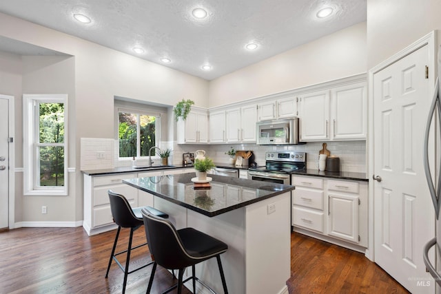 3376 E Echo Ct, Boise, ID 83712 - kitchen with stainless steel appliances, a sink, a kitchen bar, white cabinets, and recessed lighting