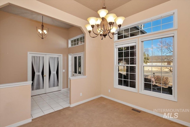 unfurnished dining area featuring carpet, french doors, visible vents, a chandelier, and baseboards