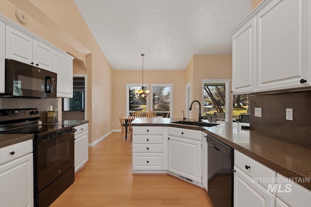 kitchen featuring a peninsula, a sink, light wood-type flooring, black appliances, and backsplash