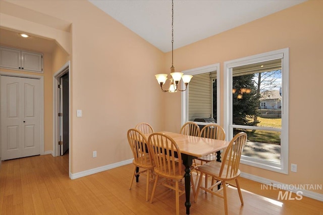 dining room featuring a chandelier, lofted ceiling, light wood-style flooring, and baseboards