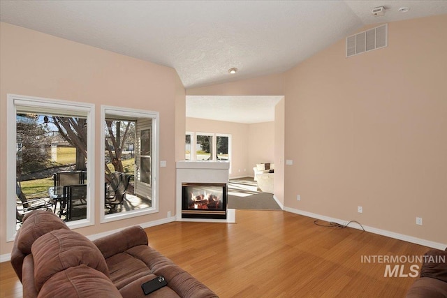 living room with lofted ceiling, visible vents, and wood finished floors