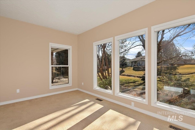 carpeted spare room with visible vents and baseboards