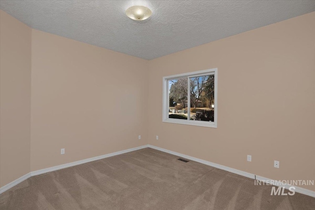 unfurnished room with carpet floors, visible vents, baseboards, and a textured ceiling