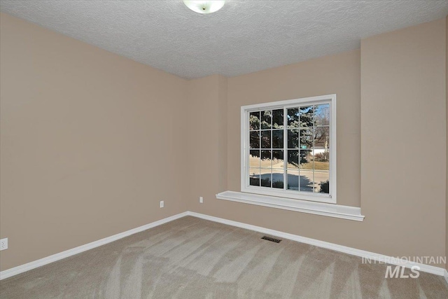 carpeted spare room with a textured ceiling, visible vents, and baseboards