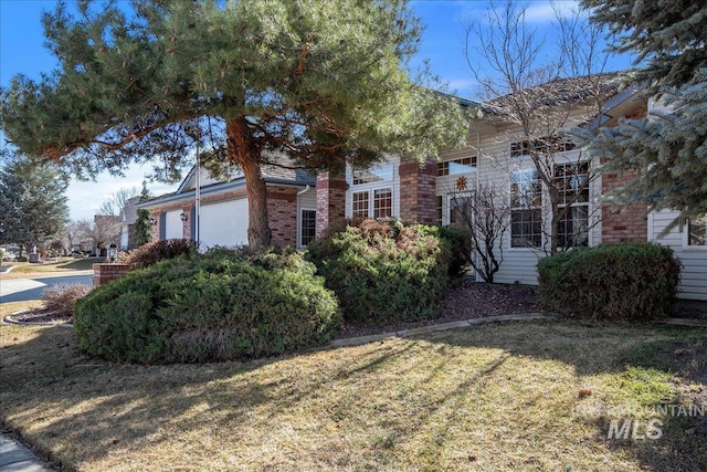 view of property exterior with a garage, a yard, and brick siding