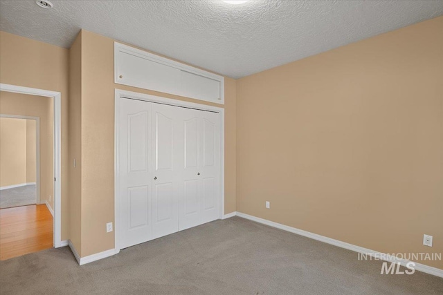 unfurnished bedroom featuring carpet floors, a textured ceiling, baseboards, and a closet