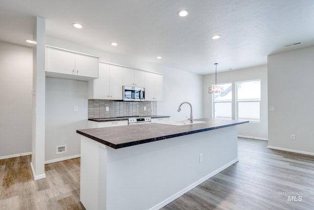 kitchen with appliances with stainless steel finishes, a kitchen island with sink, sink, and white cabinets